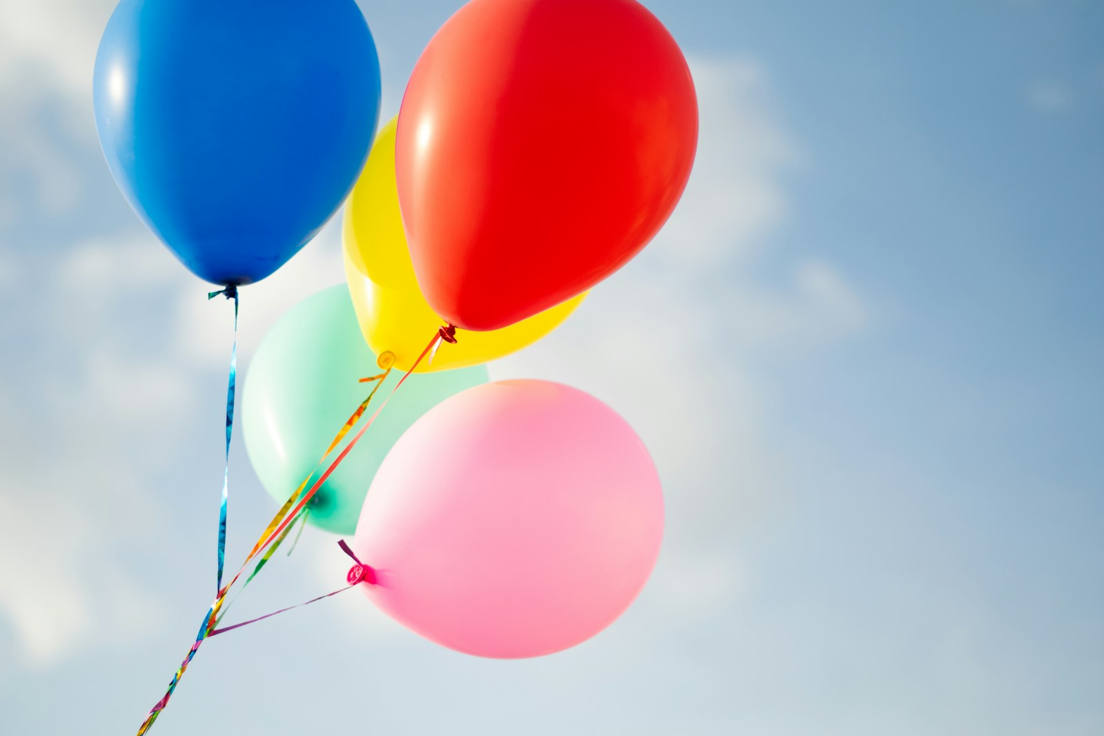 Colorful balloons float against a bright blue sky